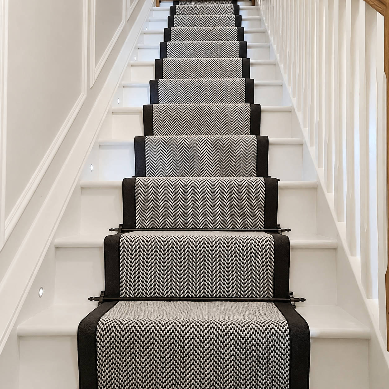 A set of carpeted stair runners with a black and white chevron pattern, installed on a white staircase.