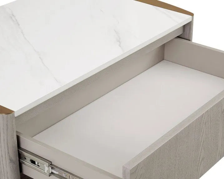 A five-drawer chest of drawers with a light gray wood grain finish and small gold-toned metal feet, shown against a plain white background.