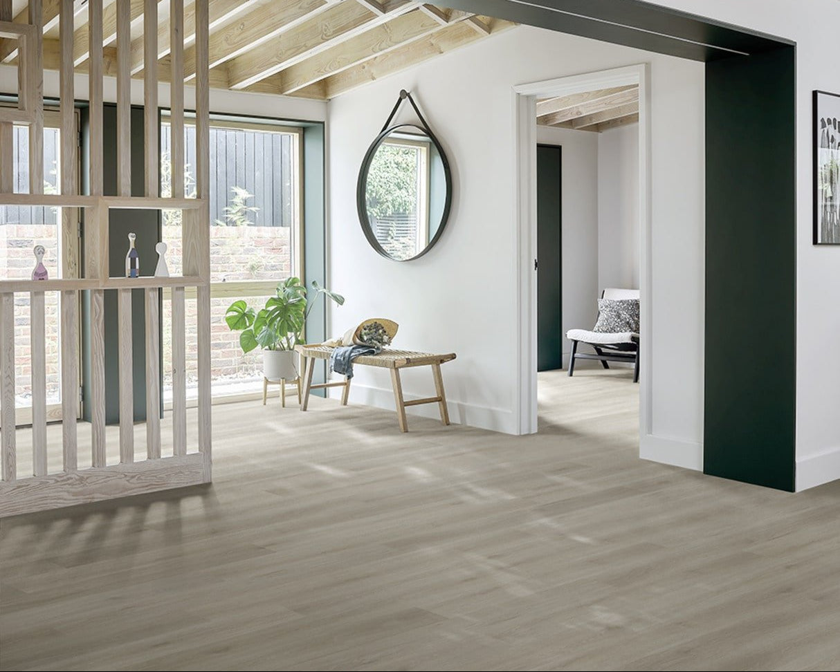Light oak wood flooring in a modern, bright interior room with white walls, a dark green accent wall, a wooden bench, and a potted plant.