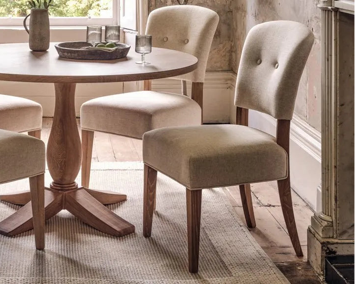set of two upholstered oak dining chairs around round dining table