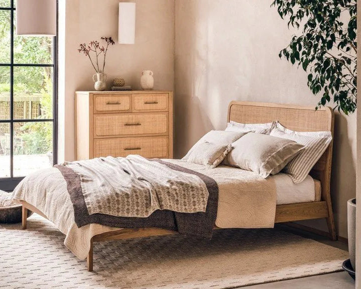 Neatly made bed with wooden headboard in a bright bedroom