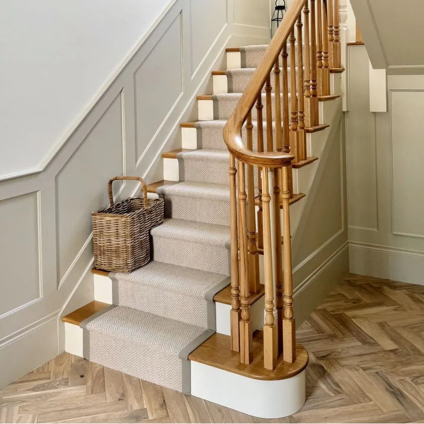 Staircase with wooden handrail and carpeted steps in a home interior.