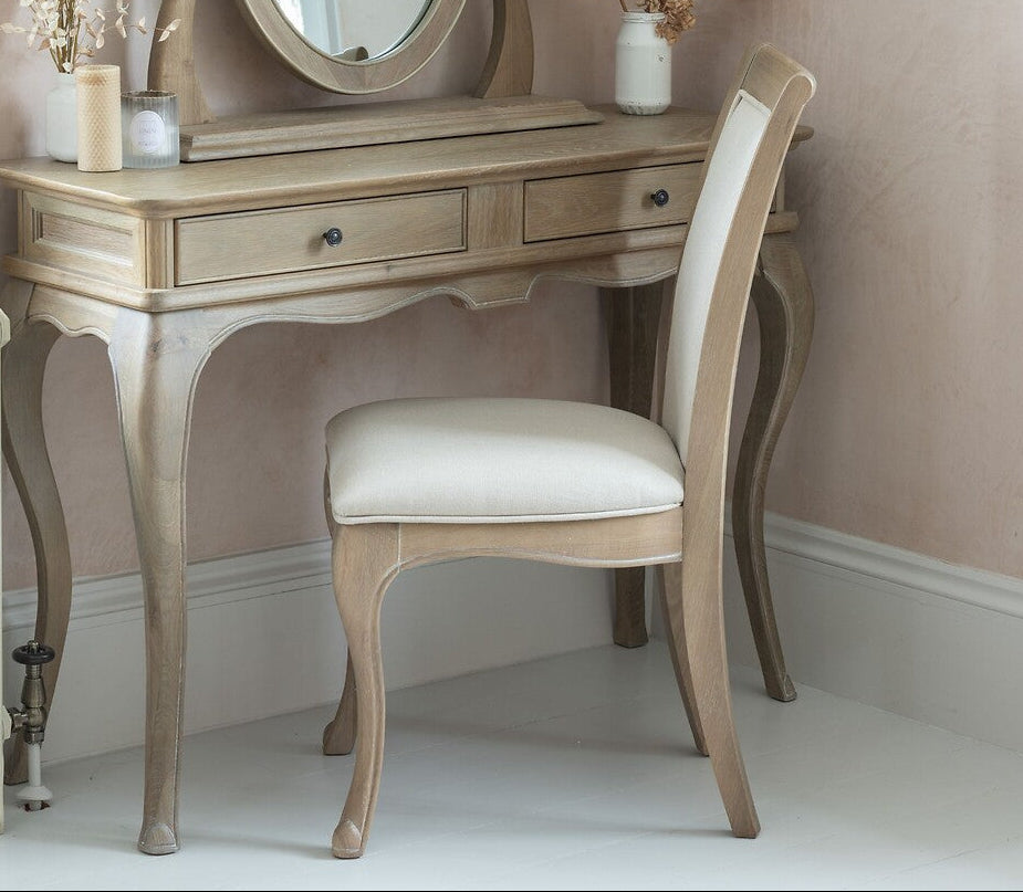 Dressing table with mirror and chair in a room with pink walls and white radiator.