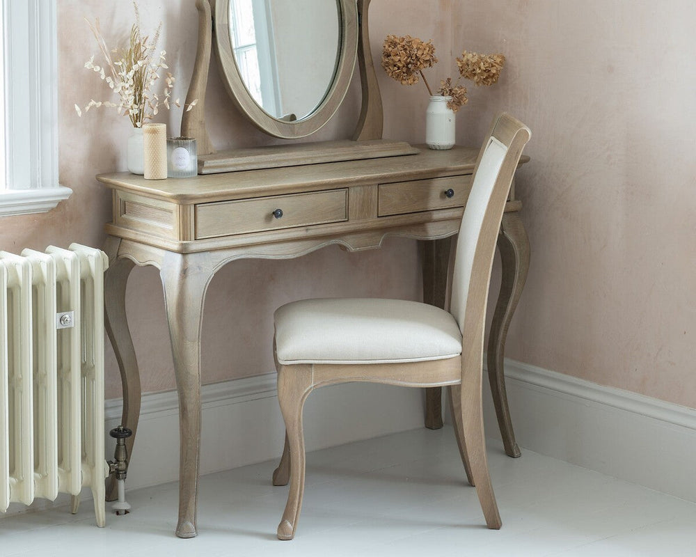 Dressing table with mirror and chair in a room with pink walls and white radiator.