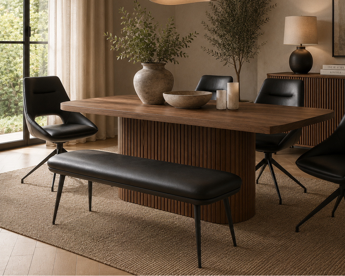 A modern dining room scene featuring a rectangular wooden dining table with a fluted pedestal base, surrounded by four black leather swivel chairs and a matching bench. The room is styled with neutral-toned decor, including a hanging pendant light, a sideboard with a lamp and framed art, and a large window with sheer curtains.