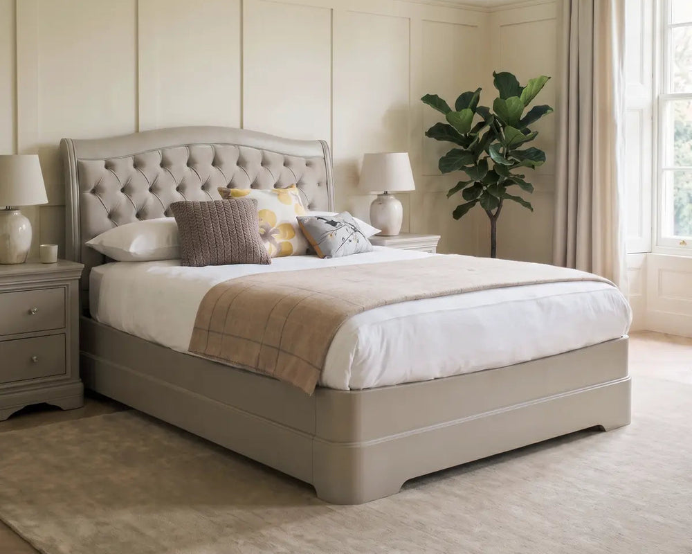 Beige bedroom with a tufted bed, nightstands, and a plant.