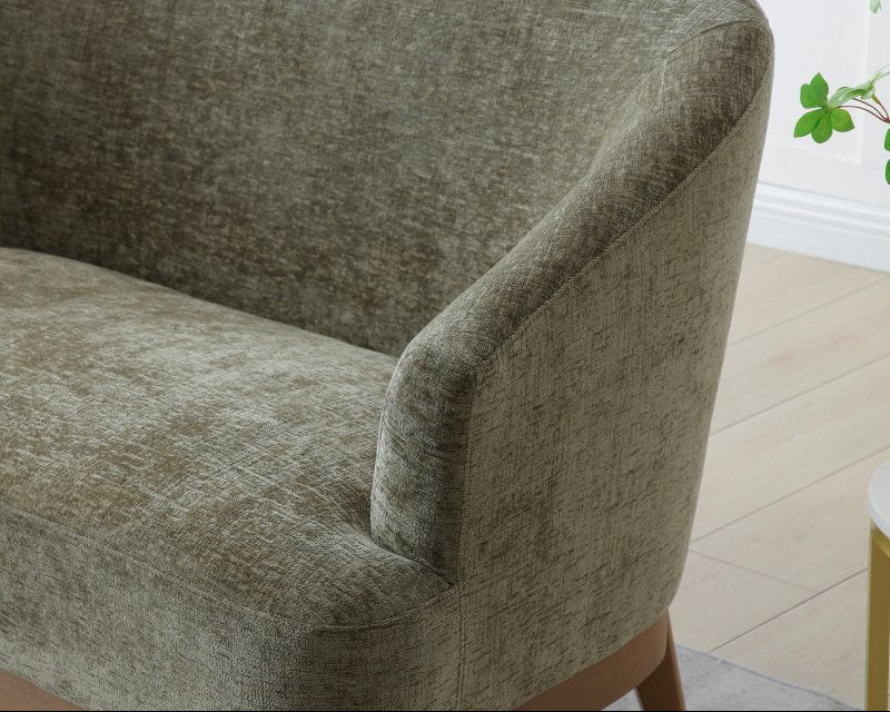 Green upholstered chair in a room with a plant and light-colored floor.