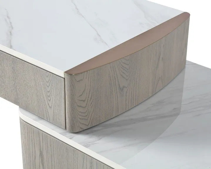 Close-up of a modern furniture piece with a white marble-look top and light gray wood grain side panels, showing a curved front edge and drawer detail on a white background.